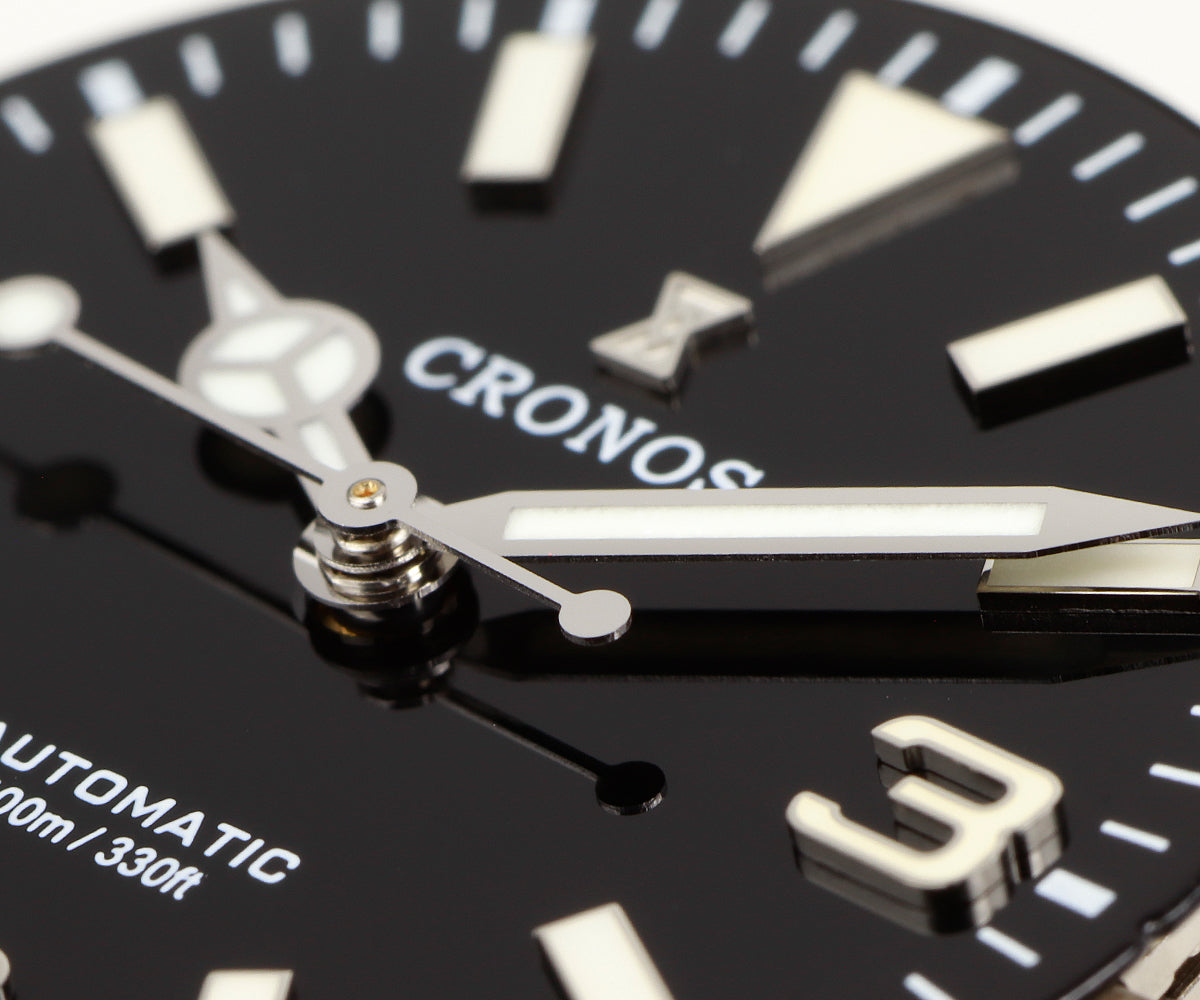 Macro photograph of the Cronos L6032 black dial, hands, applied logo and raised markers
